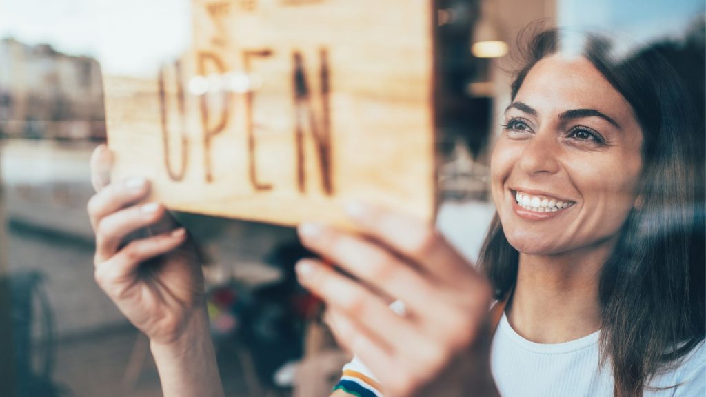 a woman flips the open/closed sign over