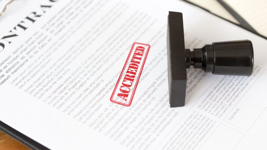 a sheath of paper is stamped by a big red capital 'accredited' mark